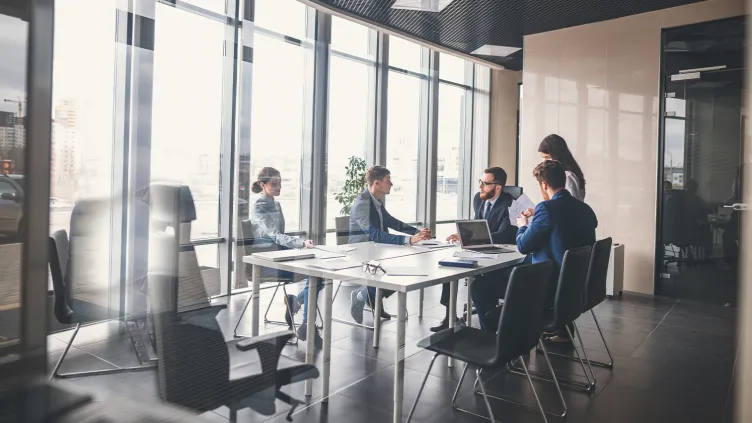 A view through the glass of a conference room of an ongoing meeting in a modern space.
